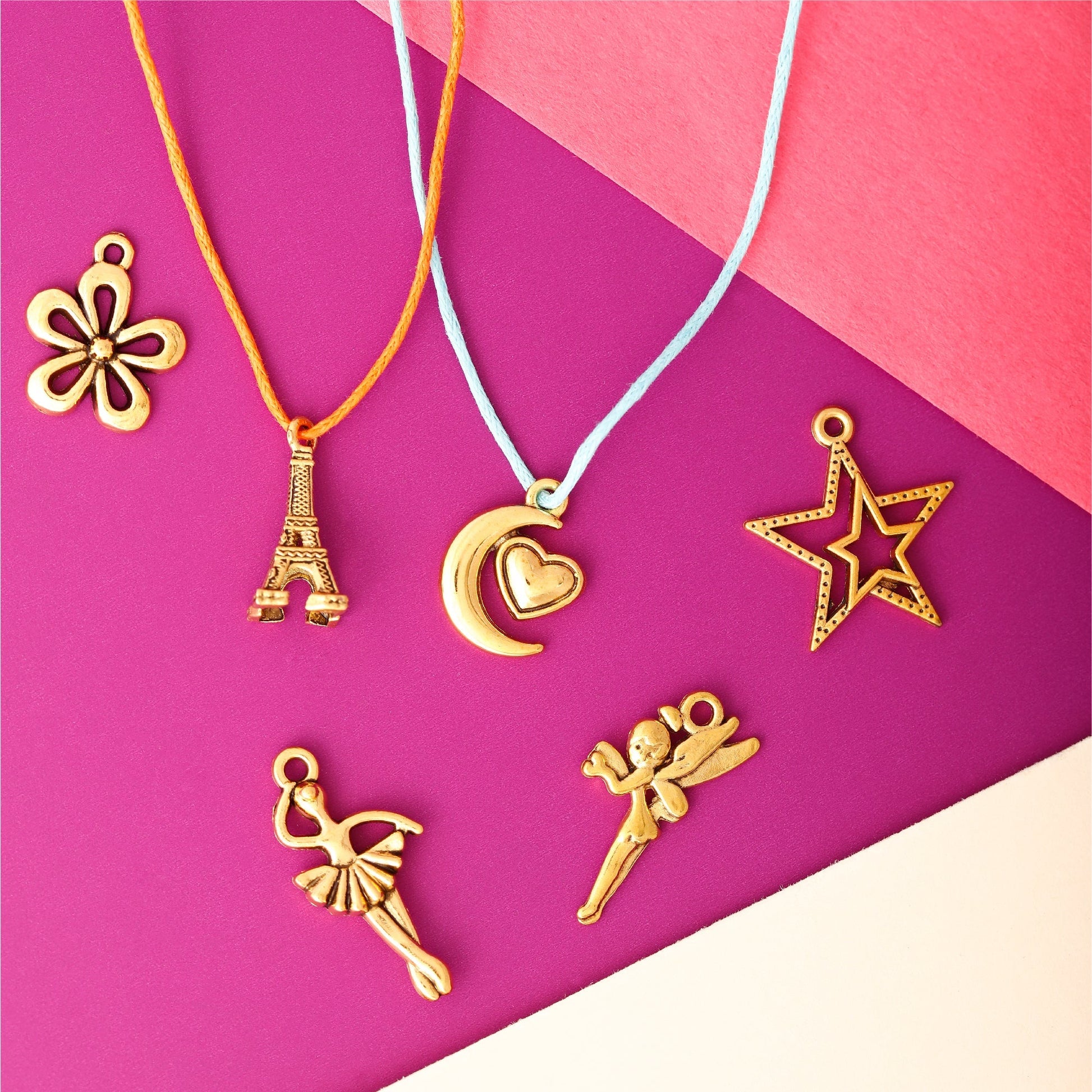 Image of Various Charm Designs from the Bulk Gold Charms Set on a Pink Background | Caption-Various Charm Designs from the Bulk Gold Charms Set on a Pink Background