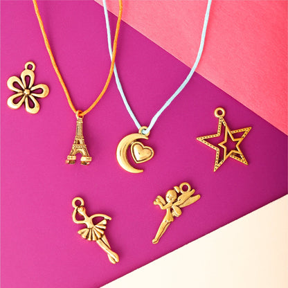 Image of Various Charm Designs from the Bulk Gold Charms Set on a Pink Background 